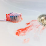 Toothbrush with blood on the bristles and blood in the sink from gum disease in jonesboro