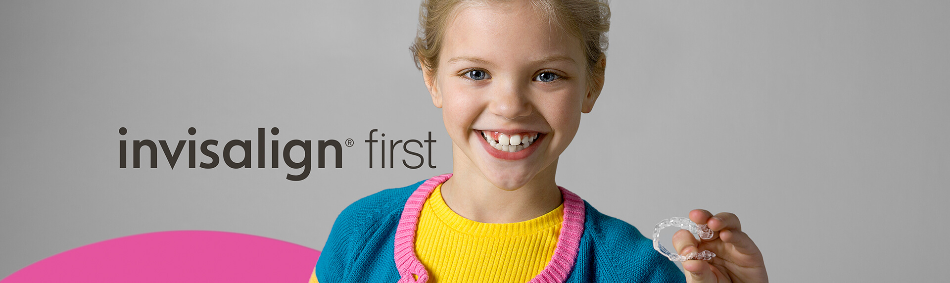 smiling girl holding an Invisalign aligner