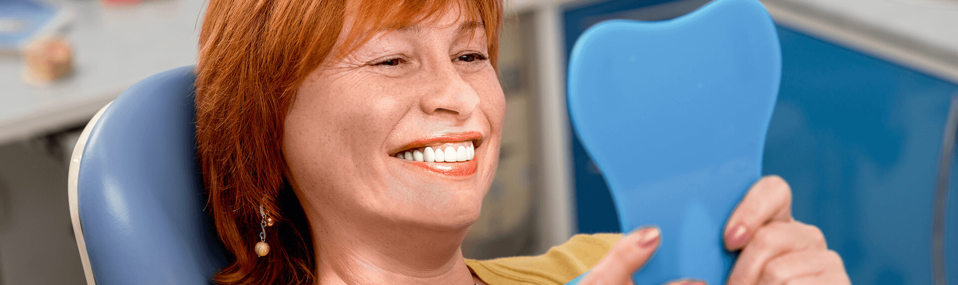 woman looking in a mirror at the dentist and admiring her teeth in jonesboro