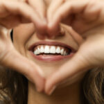 A woman holds her hands in a heart shape in front of her smile in jonesboro