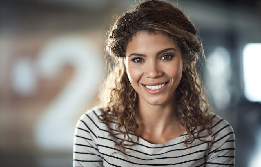 Headshot of a smiling curly-haired woman with diabetes wearing a striped shirt