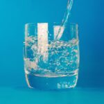 Water being poured into a glass of water against a blue background in jonesboro