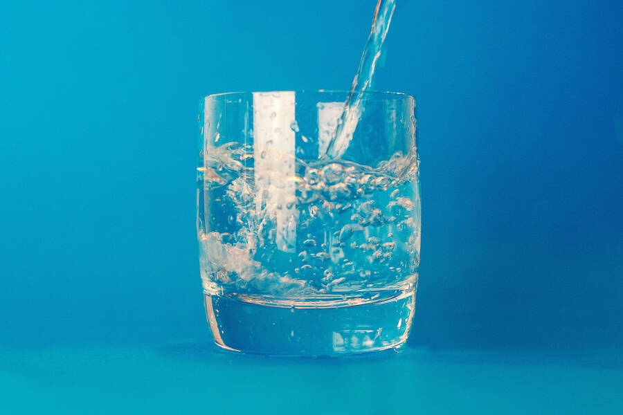 Water being poured into a glass of water against a blue background in jonesboro