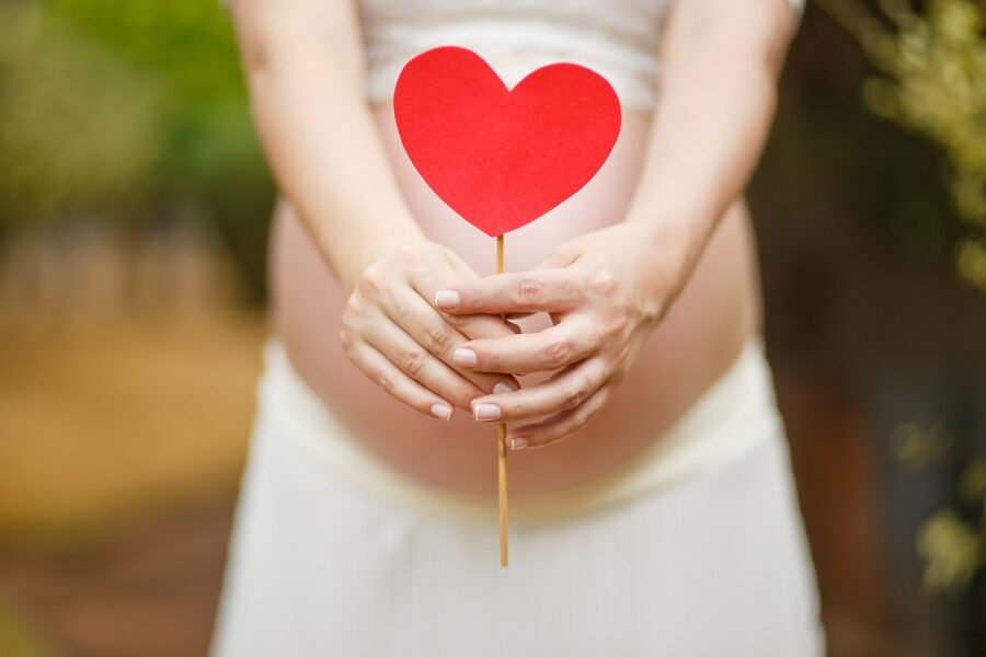 Photograph of pregnant woman's belly with a stick with a red heart on top in jonesboro