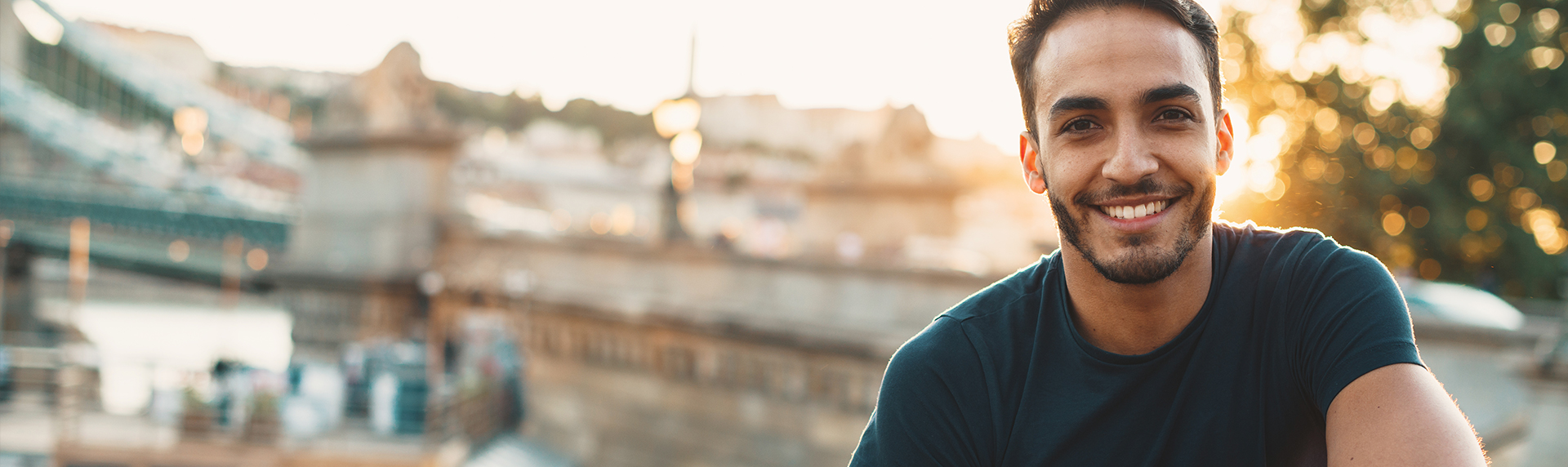 young man smiling at camera during sunset with city in the background, dental care in jonesboro