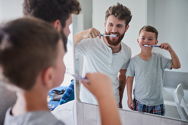 father and son brushing their teeth together