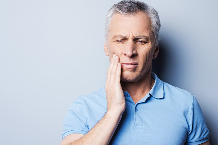 man holding his jaw in discomfort