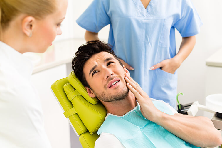 man at the dentist, holding his jaw in pain