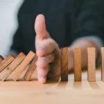 risk of skipping preventive dental care, image of a hand stopping dominos to show how catching issues early prevents bigger problems