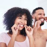 couple flossing their teeth for dental implant care