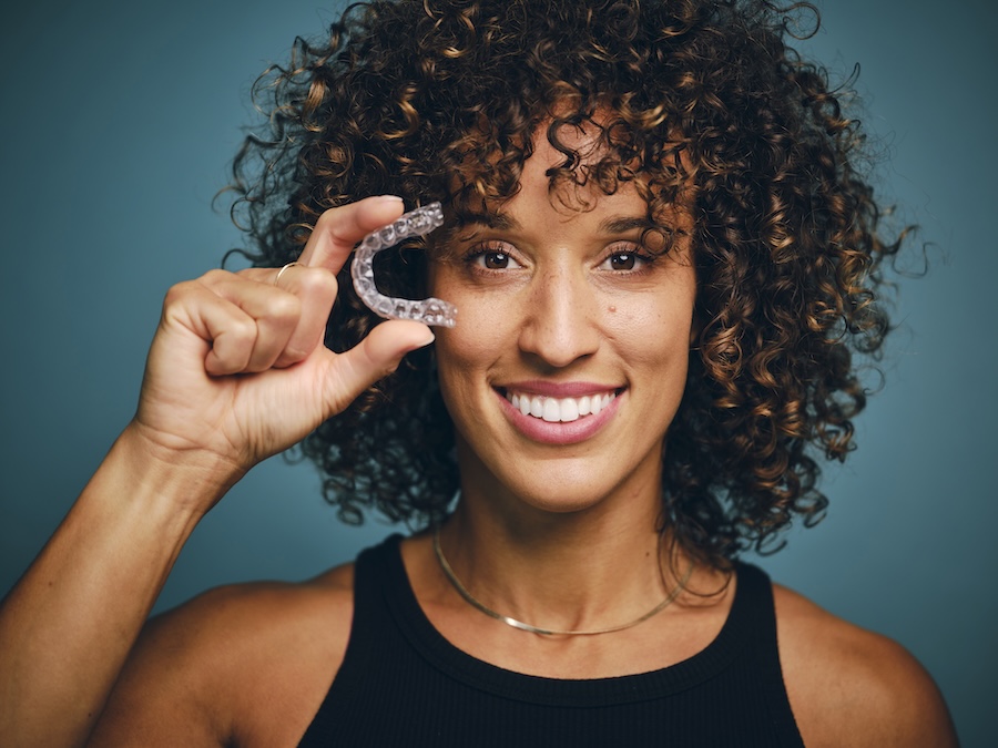 woman holding invisalign clear aligner tray for invisalign question invisalign FAQ